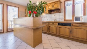 Una cocina con gabinetes de madera, una isla integrada con pileta, microondas y lavavajillas.