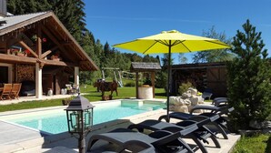 Ein Poolbereich mit Liegestühlen, einem Grill und einer Holzhütte.