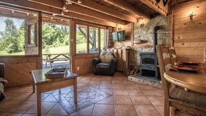 Ein rustikales Blockhaus-Interieur mit Kamin aus Stein, Holzmöbeln und einem Fernseher.