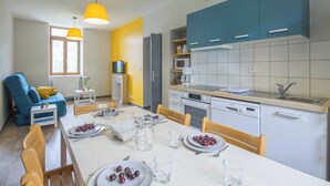 A compact living space with a dining area, kitchen, and a blue sofa.
