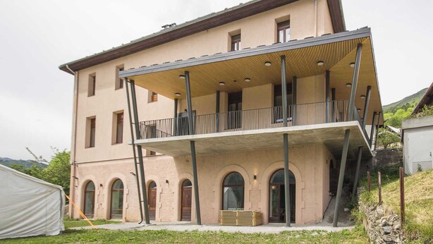 A two-story building with a flat roof and a balcony on the upper floor.