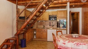 Una cocina rústica con armarios de madera, horno empotrado y comedor con mantel a cuadros.
