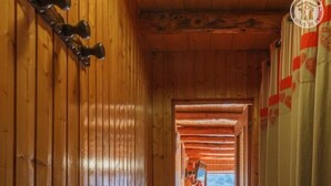 Un pasillo de madera con un banco, una mesa y una vista de la montaña a través de una ventana.