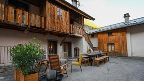 Un área de comedor al aire libre rústica, con muebles de madera y una parrilla.