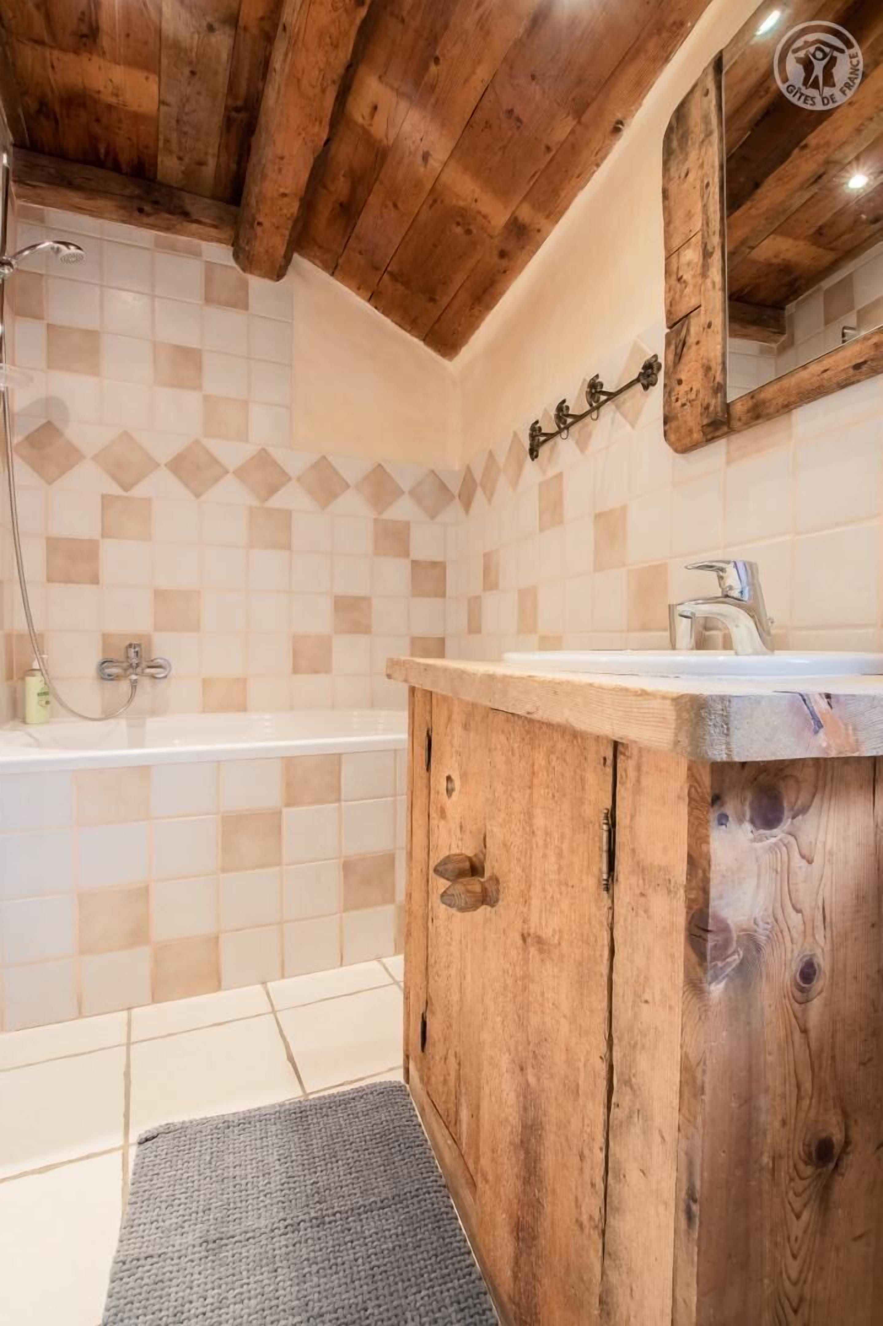 A bathroom with a wooden vanity, a bathtub, and a shower area.