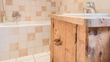 A bathroom with a wooden vanity, a bathtub, and a shower area.