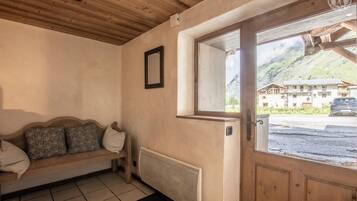 Een houten interieur met een bank, een radiator en een deur met uitzicht op de bergen.