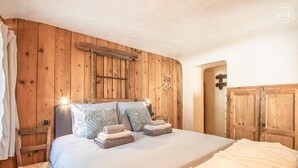 Un dormitorio con paneles de madera, una cama, almohadas y una mesita de noche.