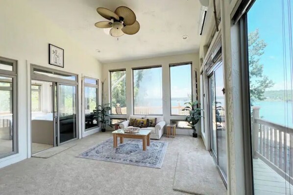 Relax in a spacious room with a high ceiling and ceiling fan, featuring a comfortable seating area and large sliding glass doors leading to an outdoor space.