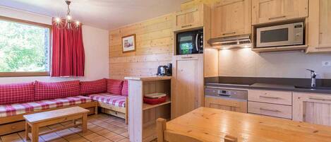 A cozy kitchen with wooden cabinets, a built-in microwave, and a dining table.