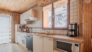 Une cuisine avec des meubles de rangement en bois, un lave-vaisselle, une cuisinière et une machine à café.