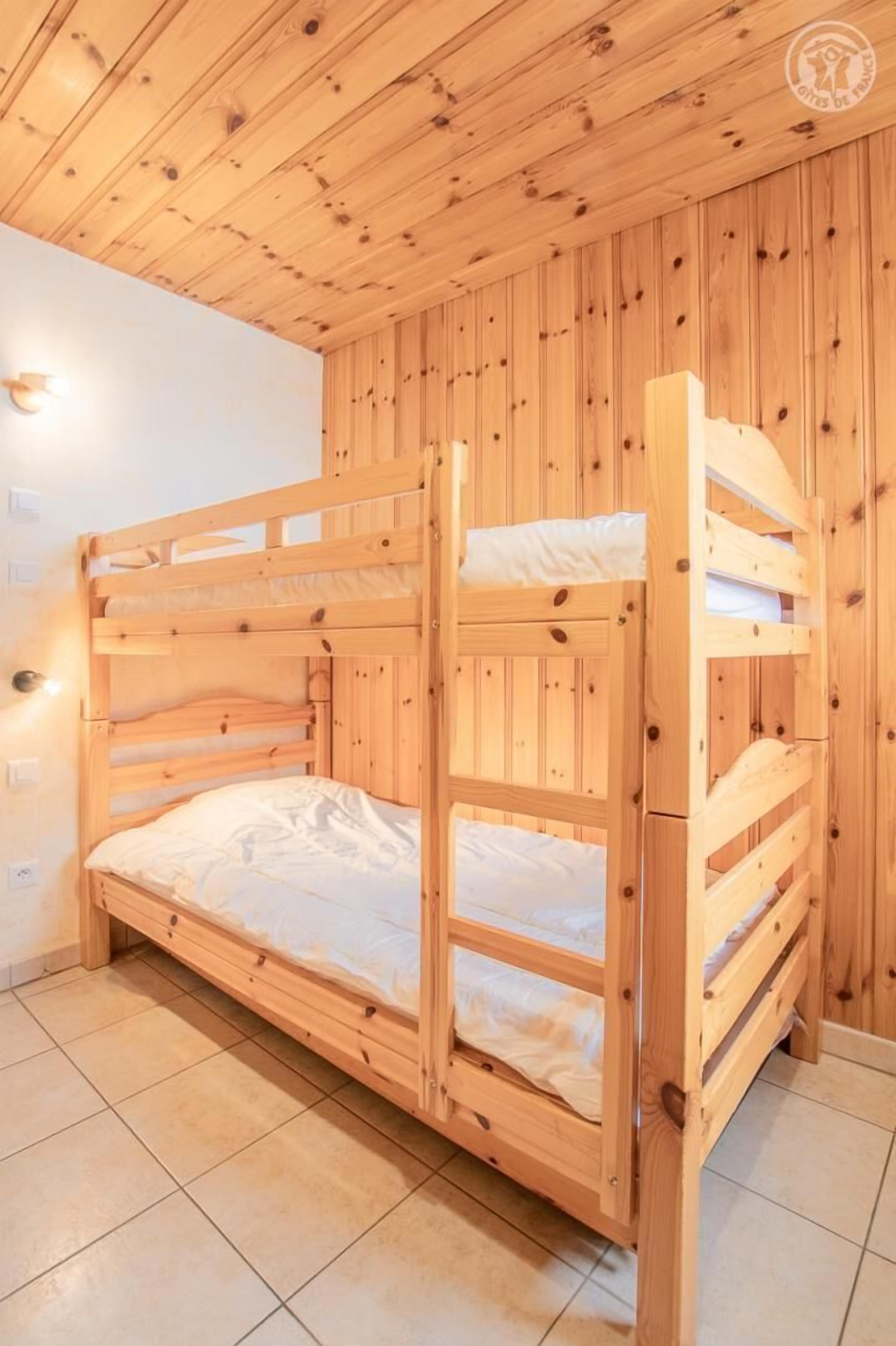 A bunk bed with wooden walls and a tiled floor.