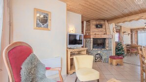 Un salon chaleureux avec une cheminée, un téléviseur et des fauteuils confortables.