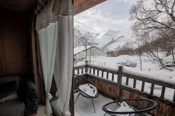 A wooden balcony with a view of a snow-covered mountain and a small house. - L'AIGLE - BONNEVAL SUR ARC (BONNEVAL SUR ARC)