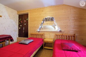 Cozy single-room accommodation with a sloped ceiling and wooden paneling, featuring a bed, nightstand, and table.