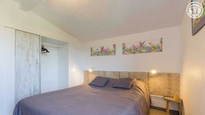 Un dormitori amb un llit gran, un armari, una petita taula de nit i decoració floral a la paret.