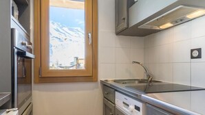 A compact kitchen with a window, stainless steel appliances, and grey cabinetry. - CHARDONNET - TIGNES - Gîte (TIGNES)