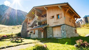 A wooden chalet with a stone base, balconies with flower boxes, and a picnic table in a mountainous area. - CHARDONNET - TIGNES - Gîte (TIGNES)