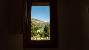 A bathroom with a window view of a mountainous landscape, a pool, and a building. - CHARDONNET - TIGNES - Gîte (TIGNES)