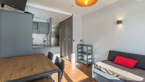 A modern apartment with a dining area, kitchenette, and a living space with a sofa and red pillow. - CHARDONNET - TIGNES - Gîte (TIGNES)