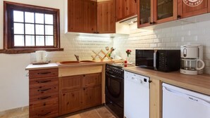 A kitchen with wooden cabinets, a white brick backsplash, a sink, a stove, a dishwasher, and a microwave. - LE RIEU - CHAMPAGNEUX (CHAMPAGNEUX)