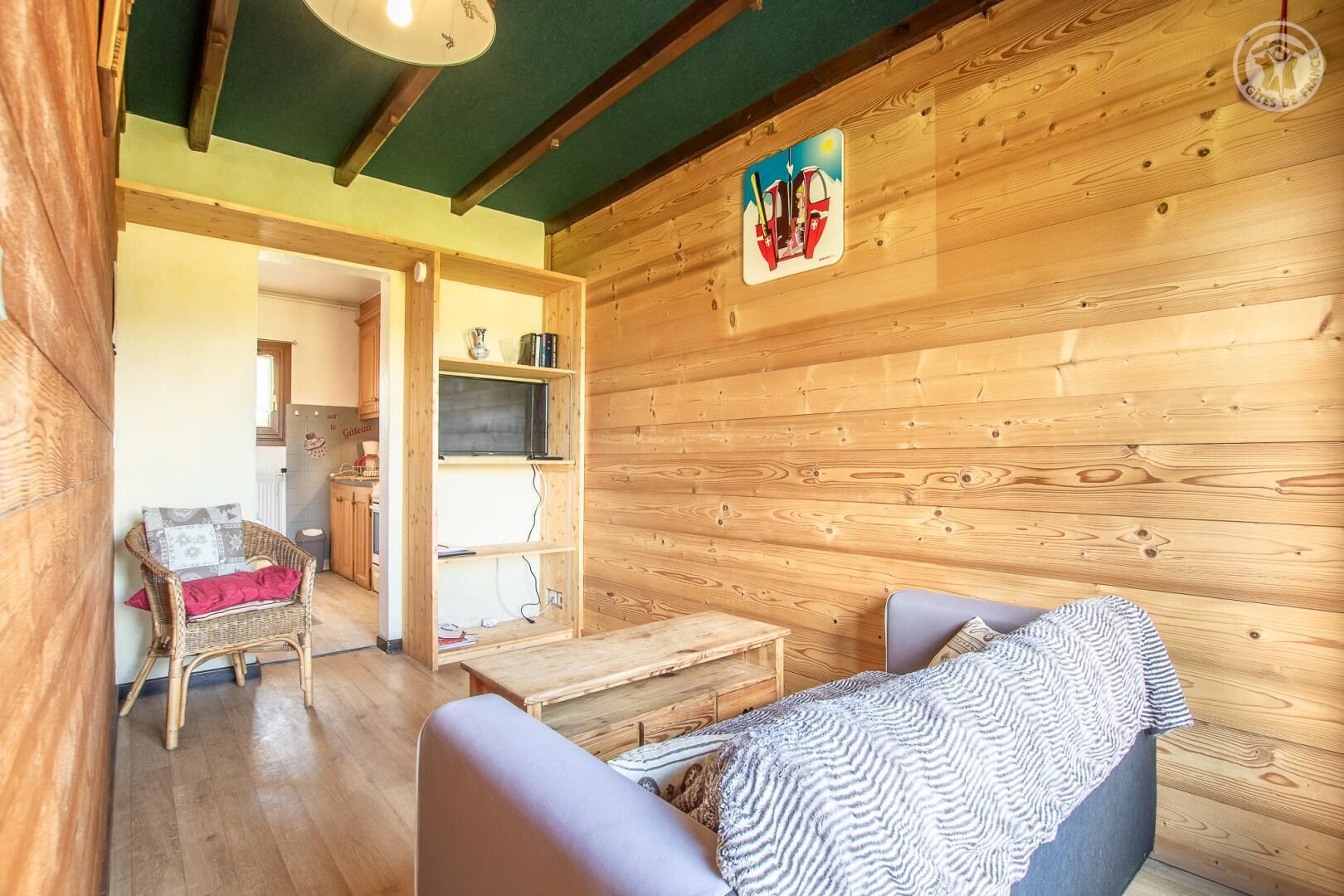 Un intérieur chaleureux, avec des éléments en bois, une chaise en osier, une petite table et un canapé.