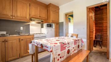 Une cuisine avec des meubles de rangement en bois, une cuisinière, un four à micro-ondes et une table recouverte d’une nappe.