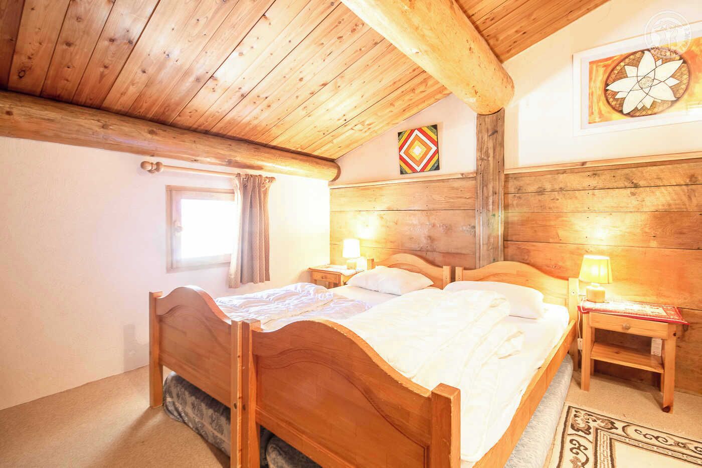 Een houten slaapkamer met een groot bed, twee nachtkastjes en een raam met gordijnen.