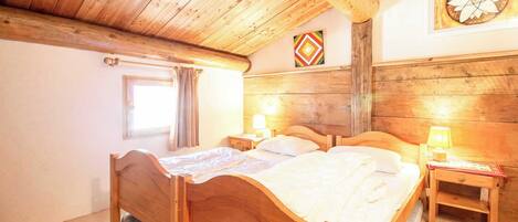 Een houten slaapkamer met een groot bed, twee nachtkastjes en een raam met gordijnen.