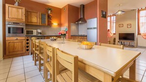 A kitchen with wooden cabinets, a central island, and a dining area. - Gîte - THOIRY - Gîte (THOIRY)