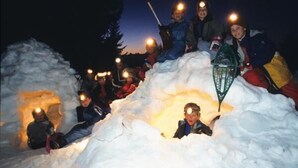 A group of people sitting in a snow mound with lights in their hands. - LACHAT - CHALET LA LICORNE (NOTRE-DAME-DE-BELLECOMBE)