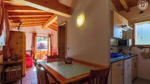 Una cucina accogliente con travi in legno, un tavolo da pranzo, sedie, un forno a microonde e un lavandino.