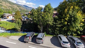 Un'area di parcheggio con auto e vista su un fiume e case sullo sfondo.