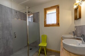 A modern bathroom with a glass shower enclosure, a yellow chair, two sinks, and a window with a wooden frame. - THE ATTIC - HAUTELUCE LES SAISIES (HAUTELUCE LES SAISIES)