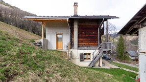 A cabin with a wooden exterior, a small porch, and a stone foundation. - LE GRENIER - HAUTELUCE LES SAISIES (HAUTELUCE LES SAISIES)