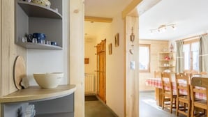 Une cuisine moderne avec des meubles de couleur grise, un plan de travail en bois et un coin repas comprenant une table et des chaises.