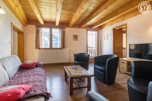 Une pièce chaleureuse avec un plafond en bois, un canapé, une table et deux chaises.
