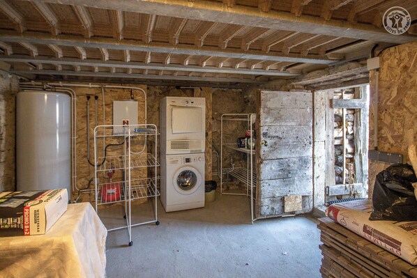 A laundry room with a washing machine, a dryer, and a metal rack with a water heater.