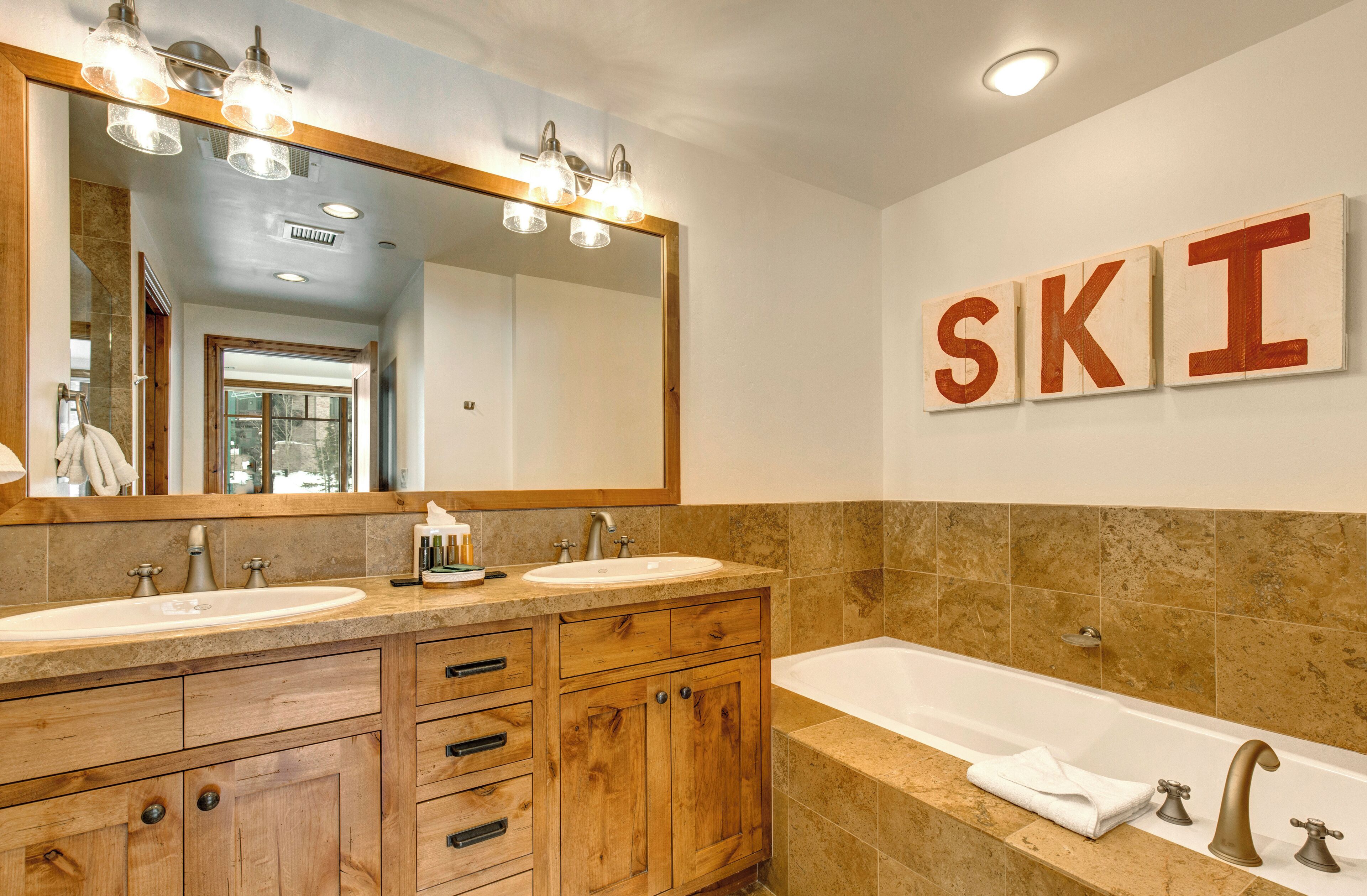 A bathroom with two sinks, a large mirror, and a bathtub.