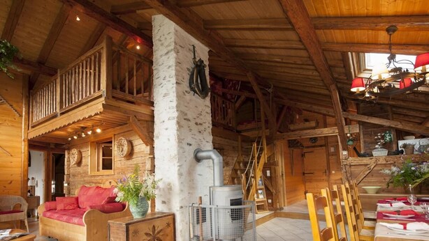A rustic wooden interior with a fireplace, wooden furniture, and a balcony.