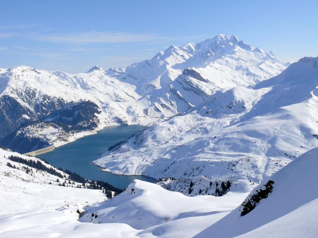 A snow-covered mountain landscape with a lake and a dam.