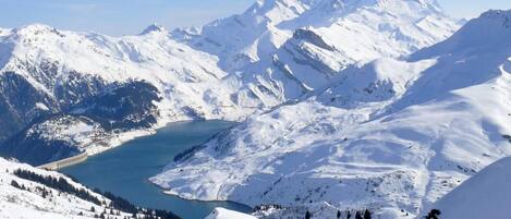 A snow-covered mountain landscape with a lake and a dam.