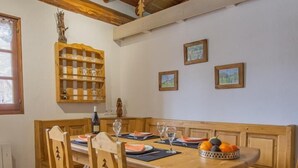 Une table de salle à manger en bois, avec des chaises, un banc et un panier de fruits.