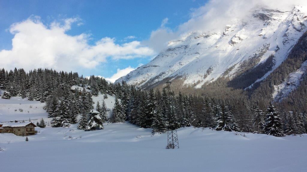 Eine verschneite Berglandschaft mit einer Holzhütte und einem Sendeturm.