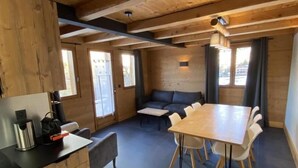 Ein gemütliches Holzhaus mit Küchenzeile, einem Esstisch und einer Couch.