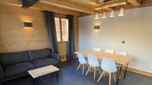Ein modernes Wohnzimmer mit einer Couch, einem Couchtisch und einem Essbereich mit Tisch und Stühlen.