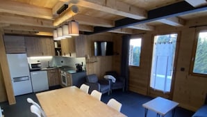 Eine moderne Küche mit Holzschränken, einem Esstisch mit Stühlen und einer kleinen Sitzecke mit Sofa und Couchtisch.