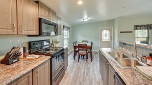 A kitchen with wooden cabinets, a stainless steel sink, and a dining area with a table and chairs. - 3 Mi to Grand Canyon Railway: Williams Retreat (Williams)
