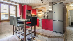 Et moderne køkken med røde skabe, rustfrie stålapparater og en bar med barstole.