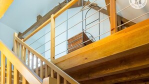 Eine Holztreppe mit Glastrennwand, die zu einer oberen Ebene führt.
